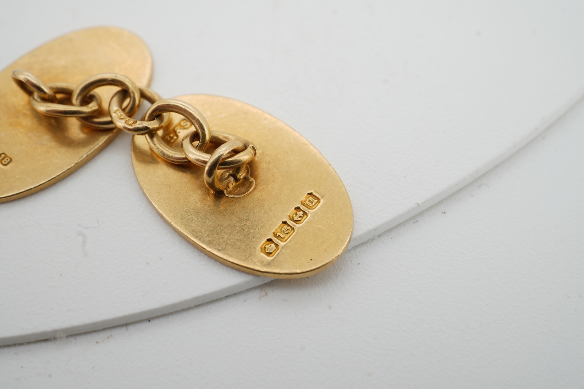 A pair of 18ct gold cufflinks, each end of oval outline, connected by chain linking, engraved with the initials RWA, length 1.8cm each, British hallmarks, combined gross weight approximately 7.5 grams